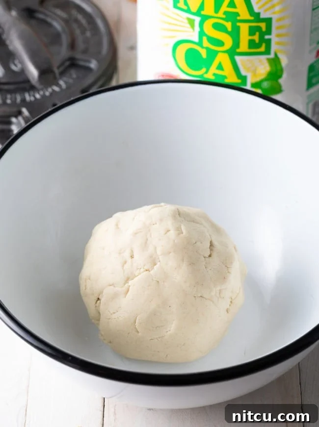 A perfectly formed, uniform ball of corn tortilla dough, showcasing its smooth texture and readiness for pressing.