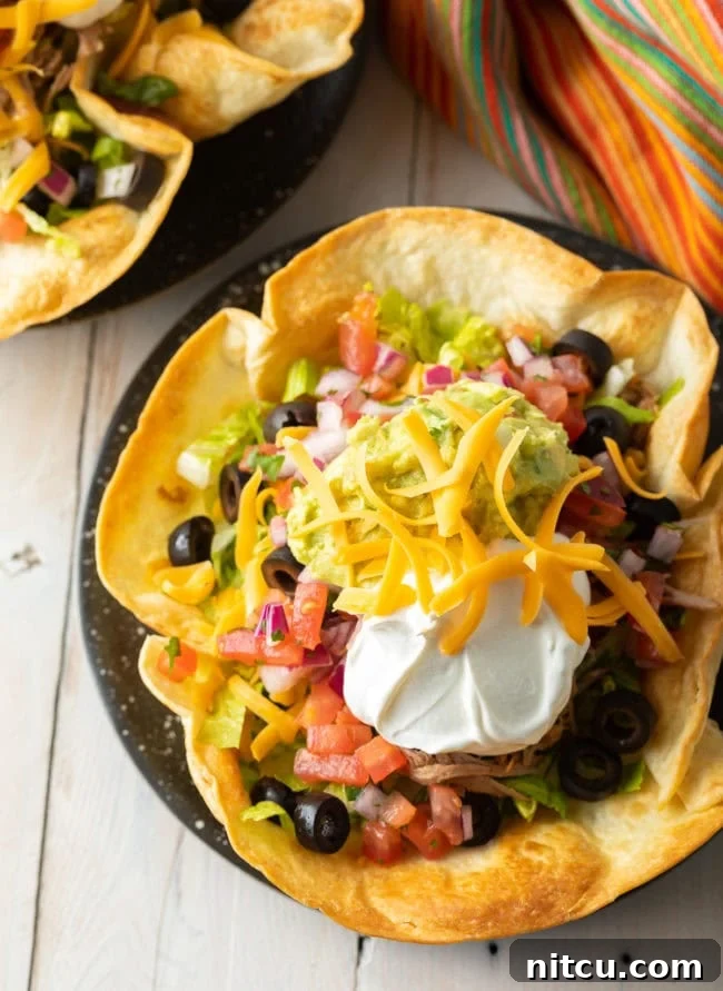 Overhead shot of a vibrant taco salad nestled in a homemade, golden-brown tortilla bowl.