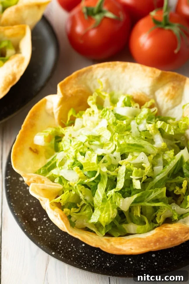 A freshly baked, crispy taco bowl shell, ready to be filled with vibrant salad ingredients.