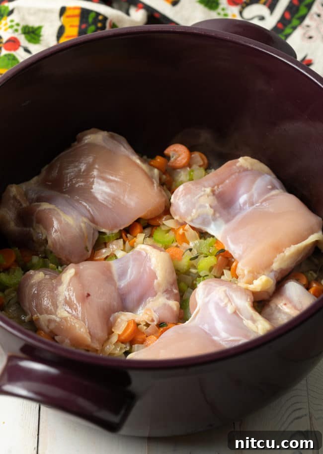 Velvety Chicken and Rice Soup 5 Chicken and various vegetables simmering in a large soup pot, creating the base for chicken and rice soup.