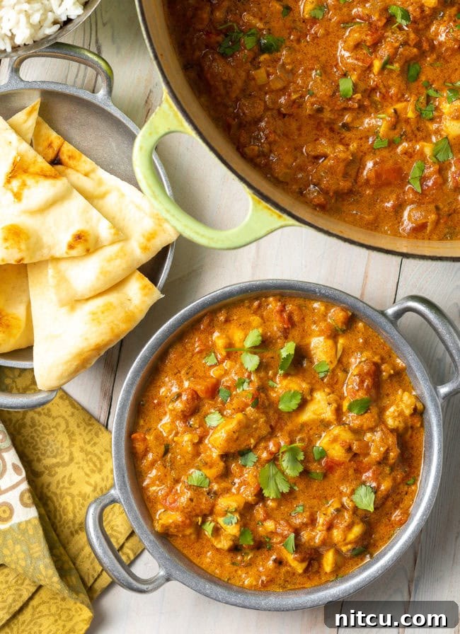 Fiery Madras Chicken 2 Easy Chicken Curry Recipe - Madras curry in a Dutch oven with more in a bowl next to some naan bread.