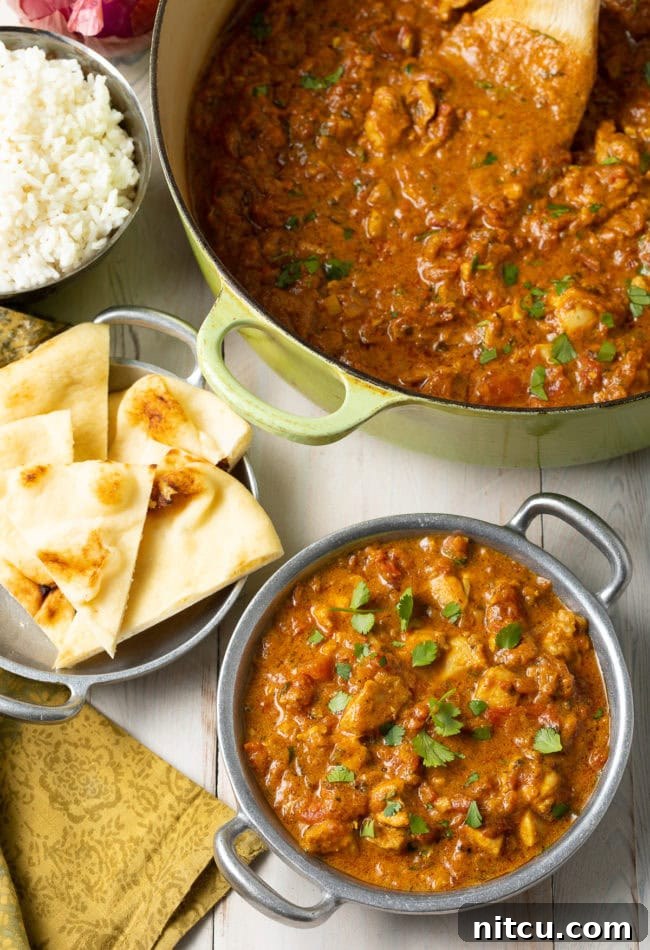 Fiery Madras Chicken 13 Madras-style chicken curry in a bowl next to naan bread.