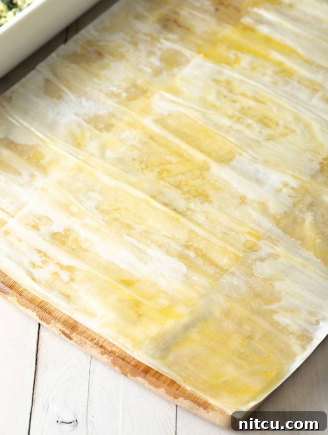 Savory Spinach Pie 12 Delicate phyllo sheets being strategically overlapped to create a wider, decorative top crust with a beautiful lip, adding character to the pie.