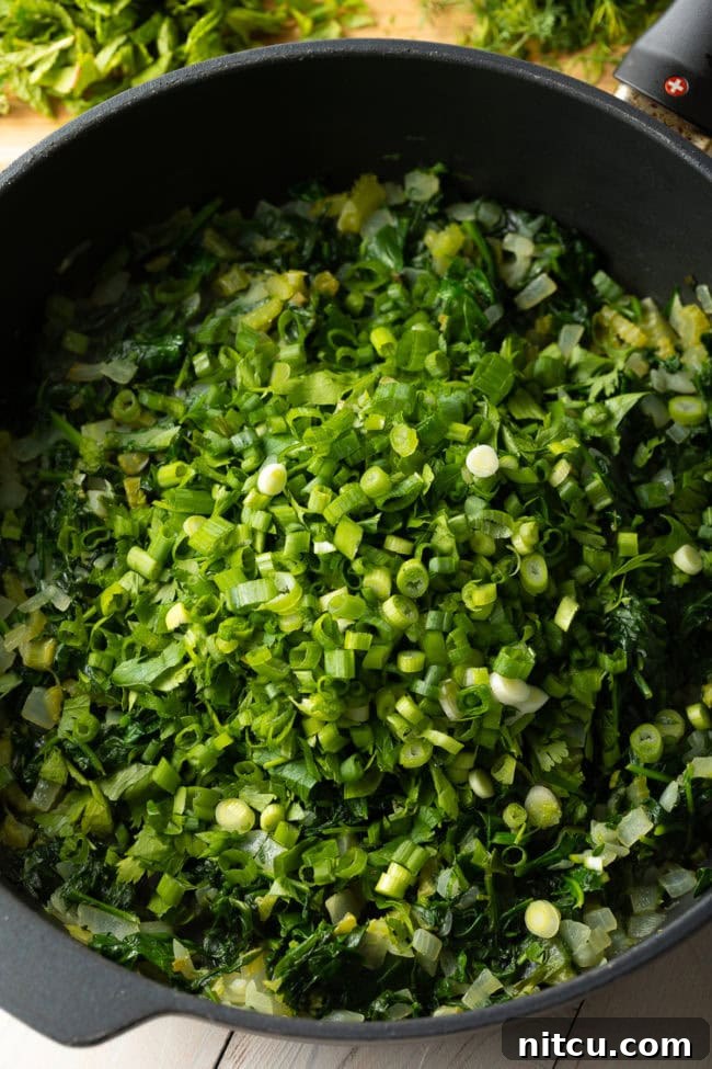 Savory Spinach Pie 5 A large pot of vibrant green vegetables, including wilted spinach and freshly added scallions, continuing to cook down for the pie filling.