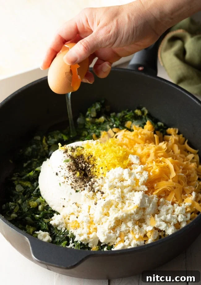 Savory Spinach Pie 6 Top-down view of the sauté pan containing the cooked greens, now thoroughly mixed with the dairy ingredients and eggs, creating a rich and homogenous pie filling.