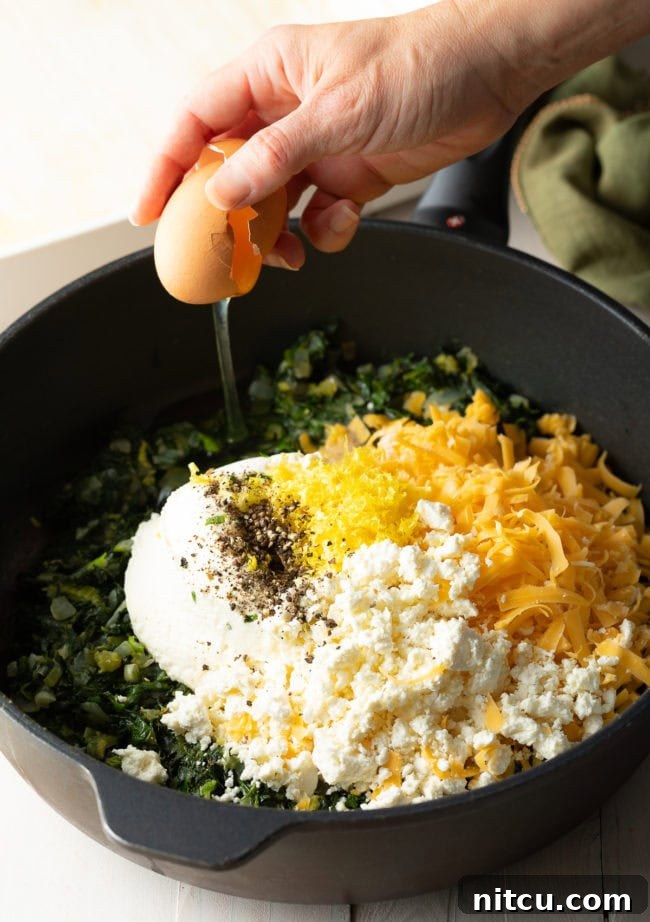 Savory Spinach Pie 7 A bowl filled with a blend of creamy ricotta, shredded cheddar, and crumbled feta cheese, poised to be mixed into the herbaceous spinach filling.