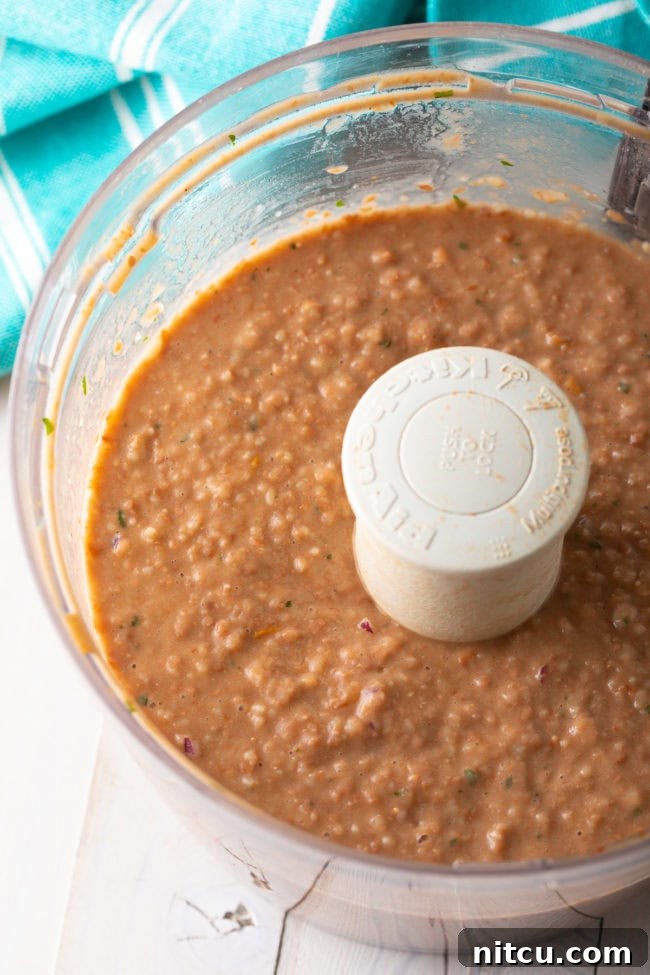 Ultimate Homemade Bean Dip 7 Food processor blending cooked pinto beans with other ingredients to create a smooth bean dip.