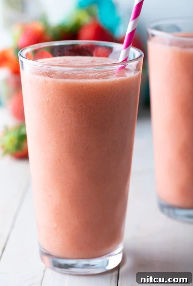 Smoothie King Caribbean Way: Your Tropical Getaway Recipe 3 Caribbean way smoothie in a tall glass with a pink striped straw.
