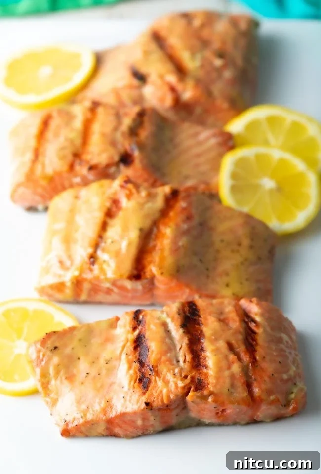 Pineapple Glazed Salmon Delight 2 Grilled salmon fillets on white platter, garnished with fresh herbs.