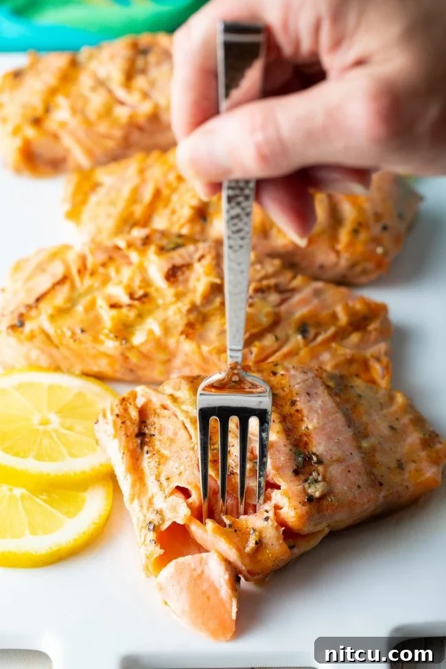 Pineapple Glazed Salmon Delight 12 Hand removing a piece of salmon with fork.