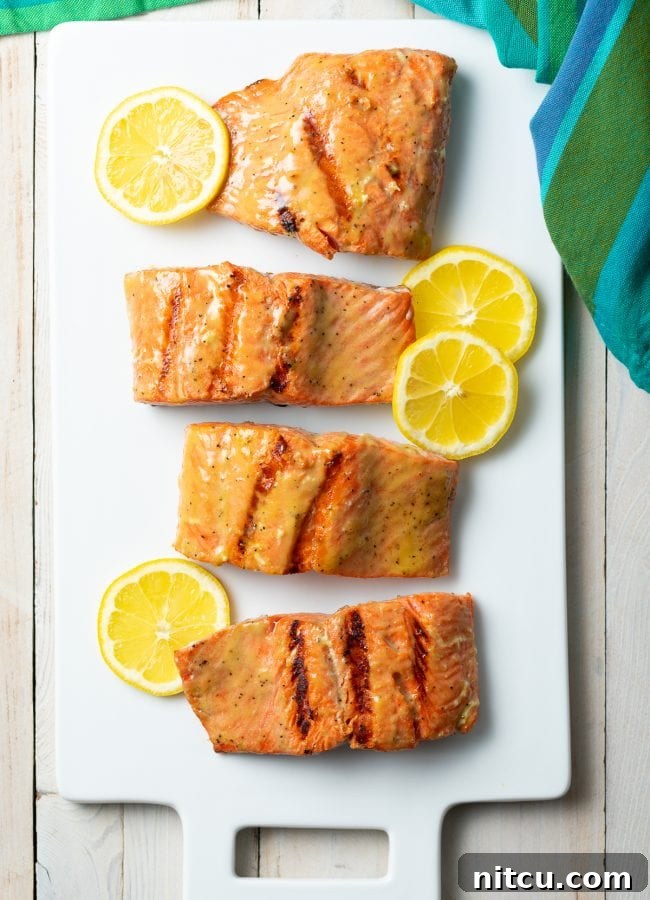 Pineapple Glazed Salmon Delight 4 Top down view of grilled salmon on a platter with slices of lemon and fresh pineapple.
