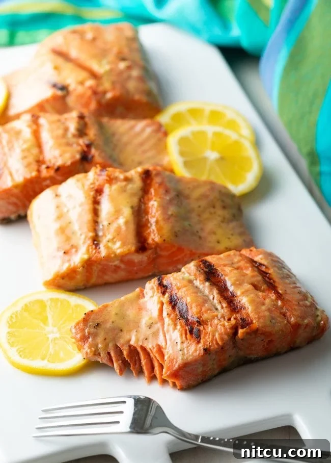 Pineapple Glazed Salmon Delight 5 Cooked salmon fillets on a white platter with a fork and bite removed.