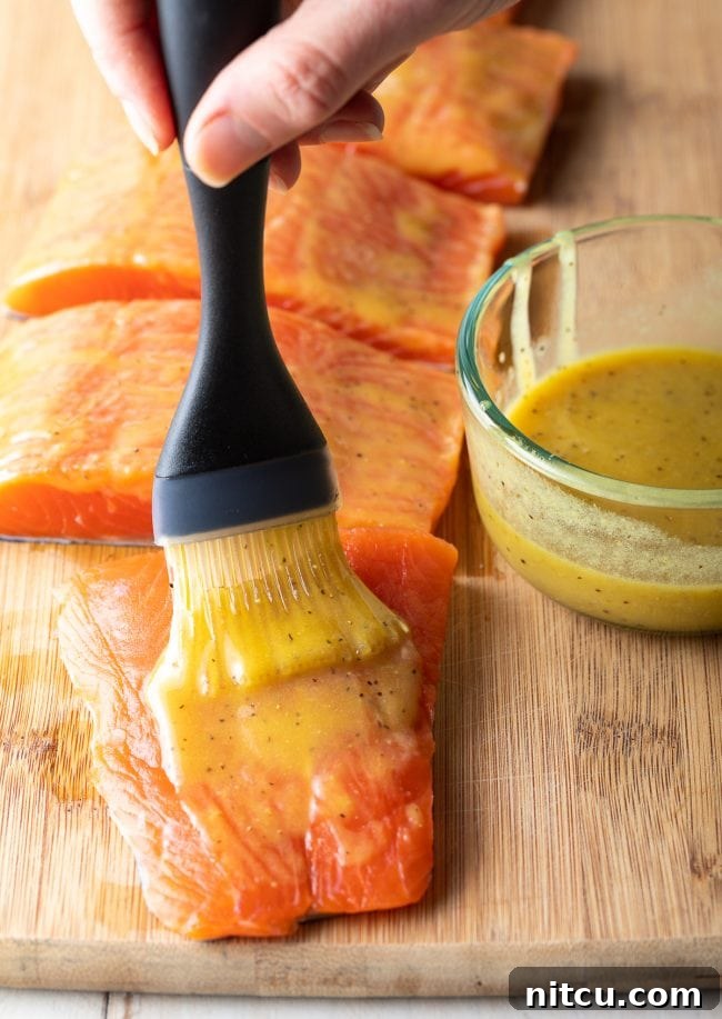 Pineapple Glazed Salmon Delight 8 A hand is brushing the marinade over the salmon fillets.