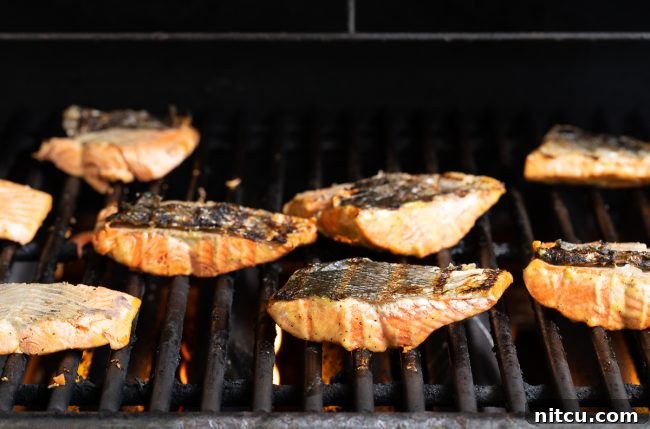 Pineapple Glazed Salmon Delight 9 Salmon fillets being grilled skin-side up on a grill.