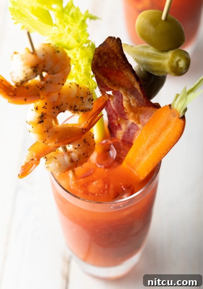 Your Signature Bloody Mary Base 4 top view of bloody mary mix recipe with shrimp skewer, bacon and a carrot on top.