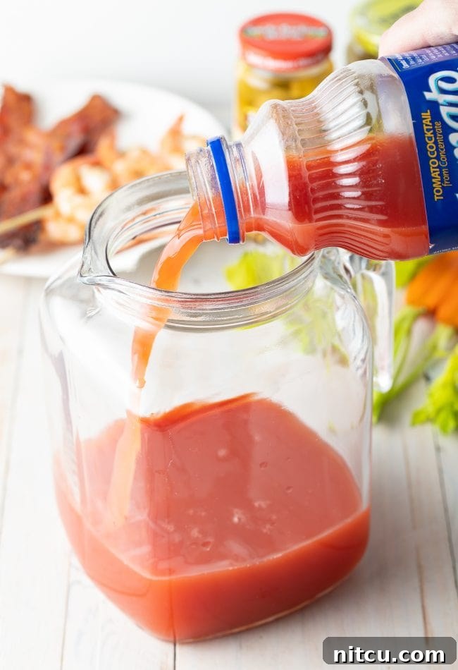 Your Signature Bloody Mary Base 6 Hand pouring Clamato juice into pitcher.