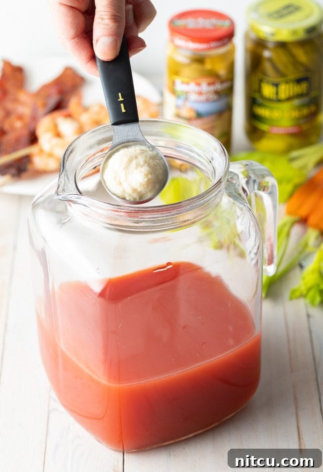 Your Signature Bloody Mary Base 7 Hand adding horseradish into pitcher.