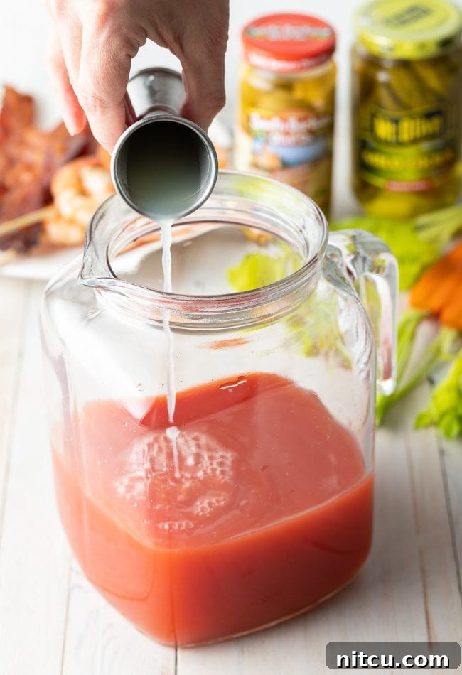 Your Signature Bloody Mary Base 8 Hand pouring lime and lemon juice into pitcher.