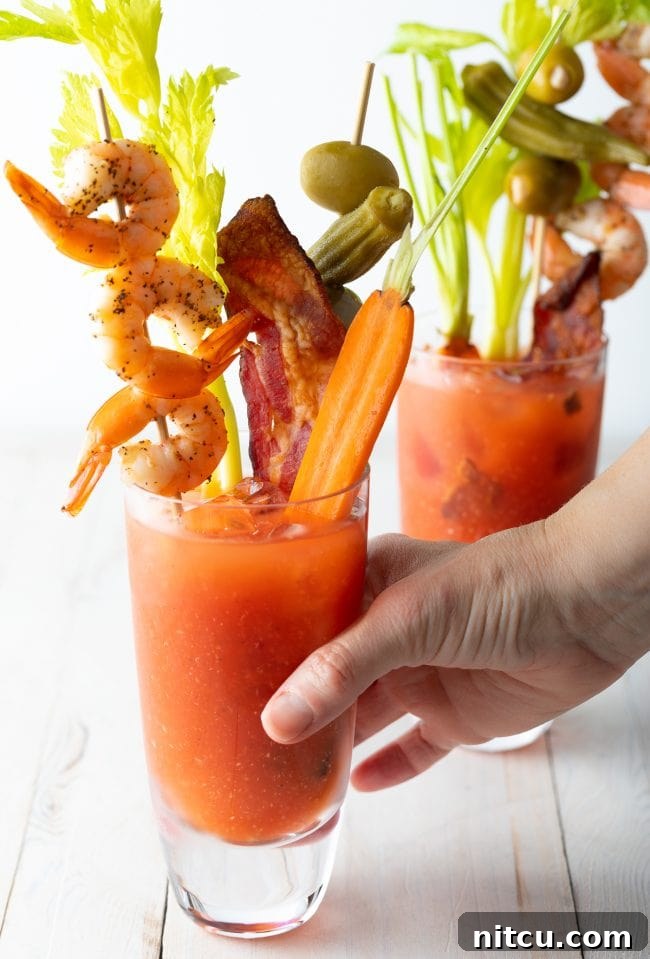 Your Signature Bloody Mary Base 10 Hand grabbing a bloody mary drink.