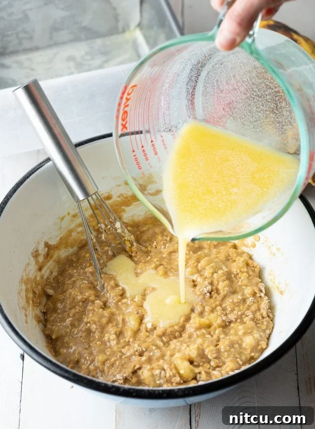 Wholesome Oat & Banana Loaf 8 Wet ingredients being carefully poured into a bowl with the mixed dry ingredients.