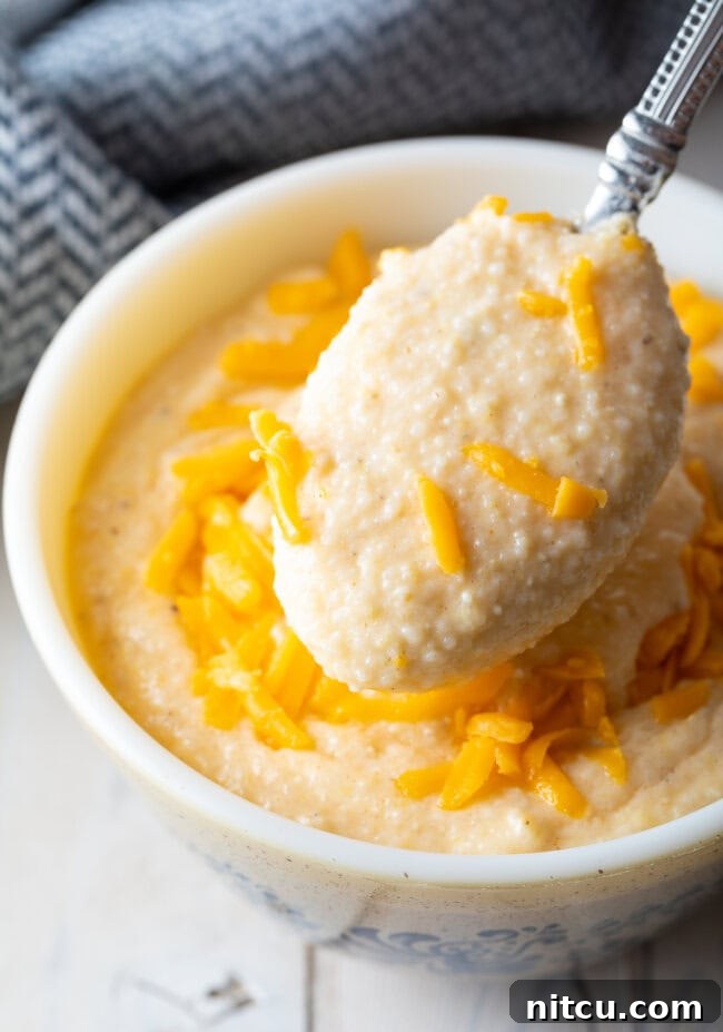 Golden Cheesy Comfort 3 Grits with cheese served in a bowl with a spoon scooping up a bite.