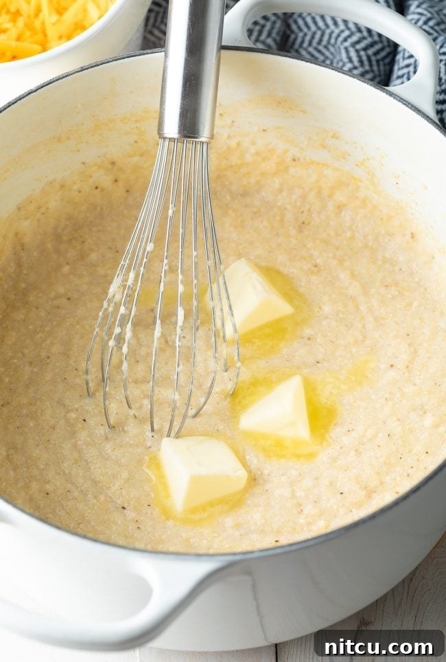 Golden Cheesy Comfort 4 Grits and butter being whisked together in a Dutch oven.