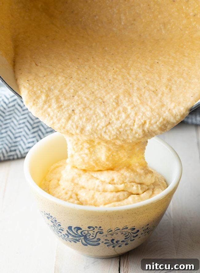 Golden Cheesy Comfort 6 Grits being poured from a pot into a serving bowl.