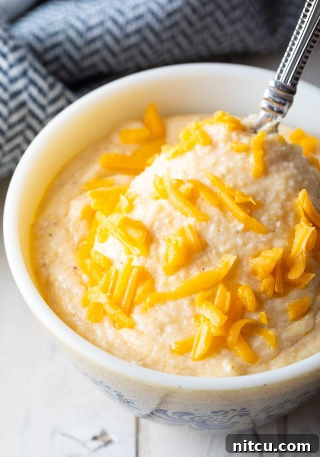 Golden Cheesy Comfort 8 Close up of cheese grits recipe in a bowl with a spoon.