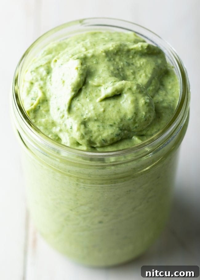 Velvety Pesto Perfection 8 A charming glass jar filled with luscious, homemade creamy pesto, sitting on a rustic wooden surface, ready to be served.