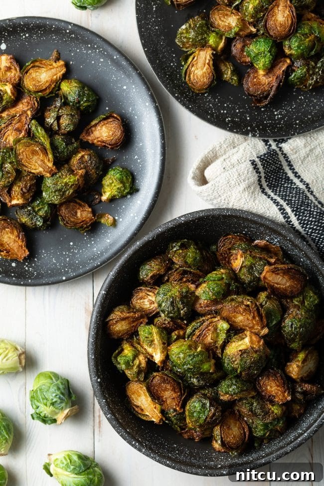 Crispy Golden Brussels Sprouts 2 Fried Crispy Brussel Sprouts in a black bowl and plate, garnished with fresh herbs.
