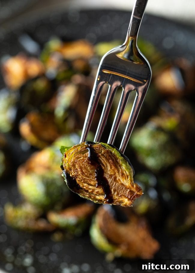 Crispy Golden Brussels Sprouts 12 Crispy Brussels sprout recipe with balsamic picked up with fork, close-up.