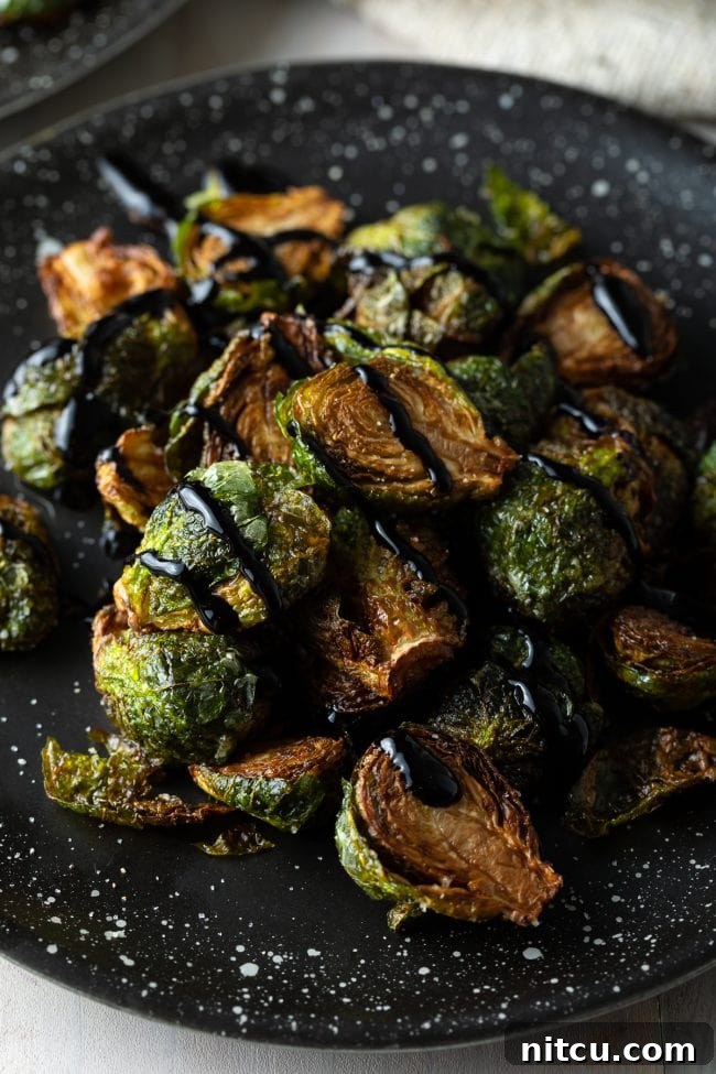 Crispy Golden Brussels Sprouts 4 Fried Brussel sprouts with balsamic glaze in black speckled plate, ready to serve.