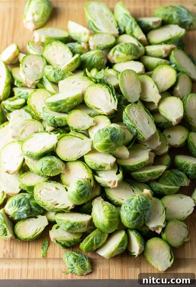 Crispy Golden Brussels Sprouts 6 Fresh sprouts cut in half on bamboo cutting board, showing preparation.