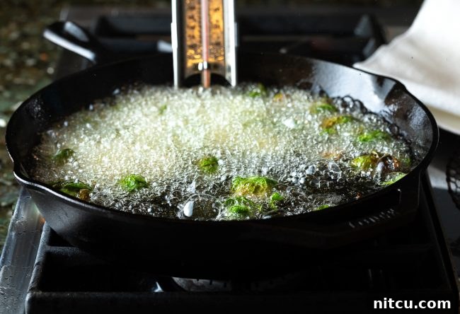 Crispy Golden Brussels Sprouts 7 Fried Brussels sprouts cooking in hot oil in a skillet, capturing the frying process.