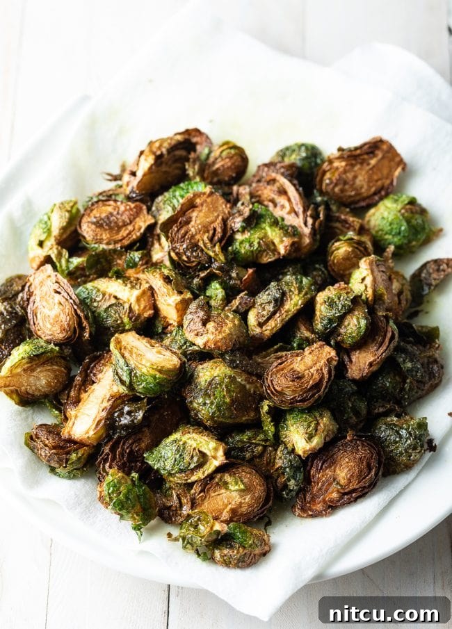 Crispy Golden Brussels Sprouts 8 Fried Brussels sprouts being strained on kitchen paper on a plate, removing excess oil.