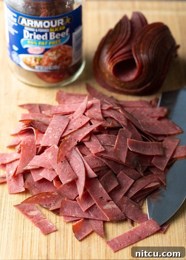 Classic Creamed Beef Toast 5 Thin strips of Buddig dried beef laid out on a wooden cutting board, ready for preparation.