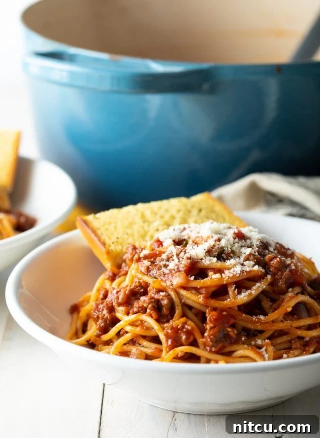 The Ultimate Spaghetti and Meat Sauce 7 spaghetti sauce recipe with meat in bowl with garlic bread.