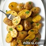 Zesty Greek Lemon Garlic Potatoes 9 Miniature potatoes with lemon slices and herbs.