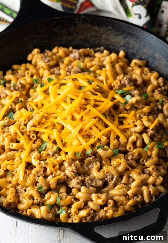 Garnished Cheeseburger Macaroni A large skillet of homemade cheeseburger mac and cheese, generously garnished with fresh chopped parsley and a sprinkle of shredded cheddar.