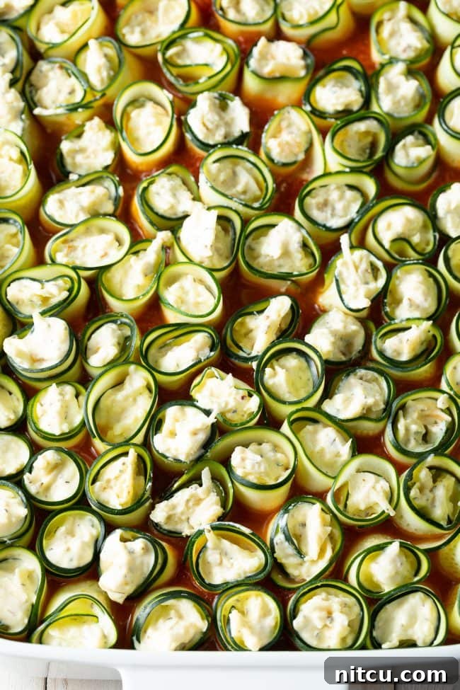 Keto zucchini noodles stuffed with cheese, arranged neatly in a baking dish before baking.