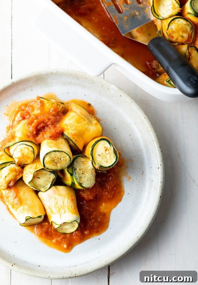 A plate of low carb lasagna roll ups alongside the baking dish full of more rolls, ready to serve.