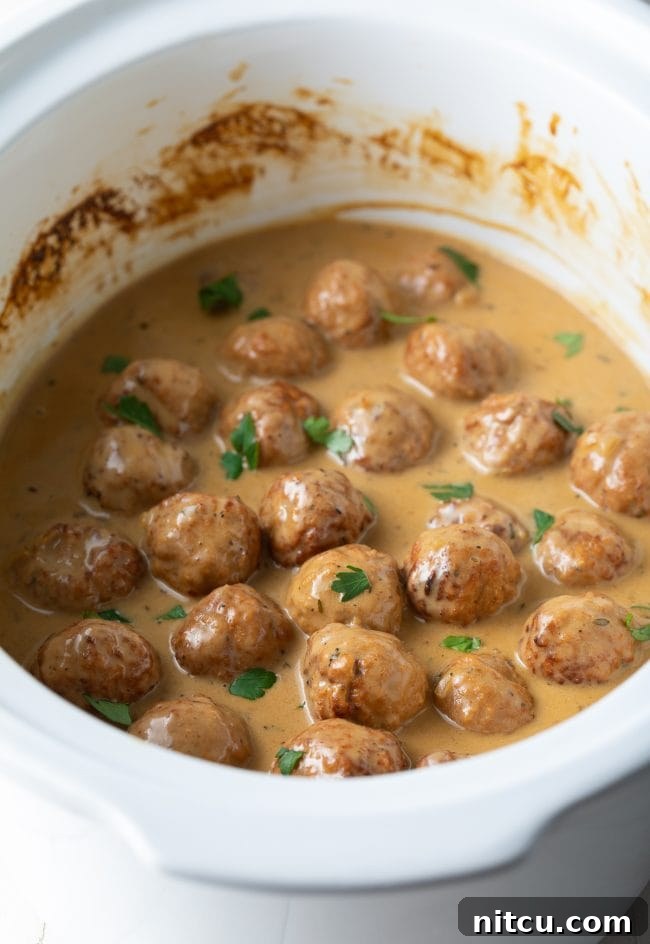 Effortless Slow Cooker Swedish Meatballs 8 Close-up of Crockpot Swedish Meatballs garnished with vibrant fresh chopped parsley, ready to be enjoyed.