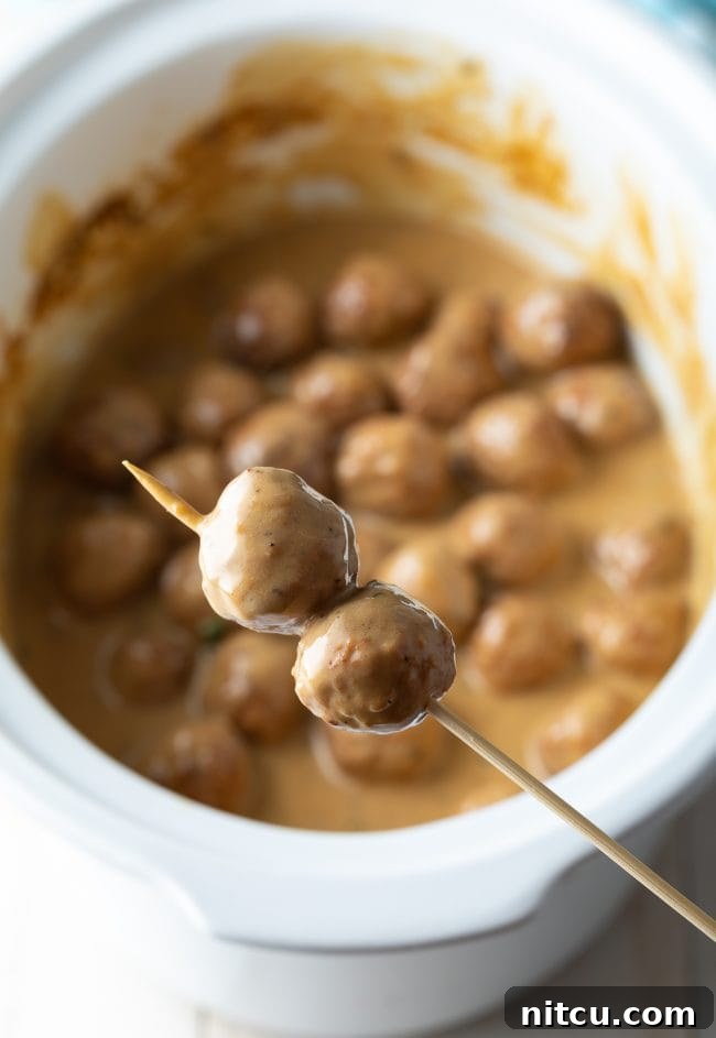 Effortless Slow Cooker Swedish Meatballs 9 Cocktail party meatballs on a wooden party pick, ready to be served as an easy appetizer.