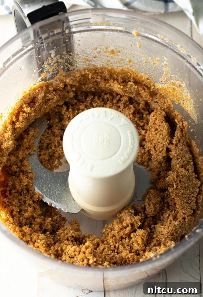 Pecan Praline Cheesecake Delight 7 The graham cracker crust mixture being pulsed in a food processor, showing the crumbs being formed.