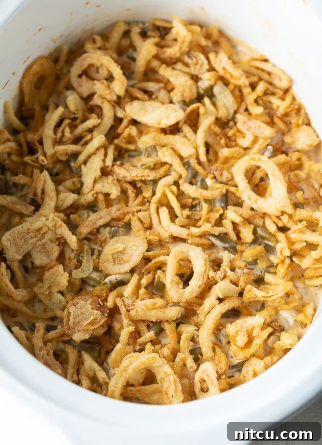 Ultimate Cream Cheese Slow Cooker Green Bean Casserole 3 Hearty Green Bean Casserole simmering in a slow cooker, featuring a rich, creamy sauce and ready for its crispy onion topping.