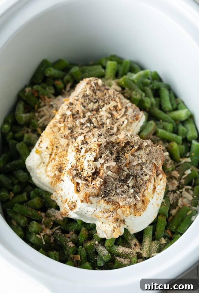 Ultimate Cream Cheese Slow Cooker Green Bean Casserole 5 A vibrant flat lay of Crockpot Green Bean Casserole ingredients: frozen green beans, softened cream cheese, onion soup mix, and sour cream.