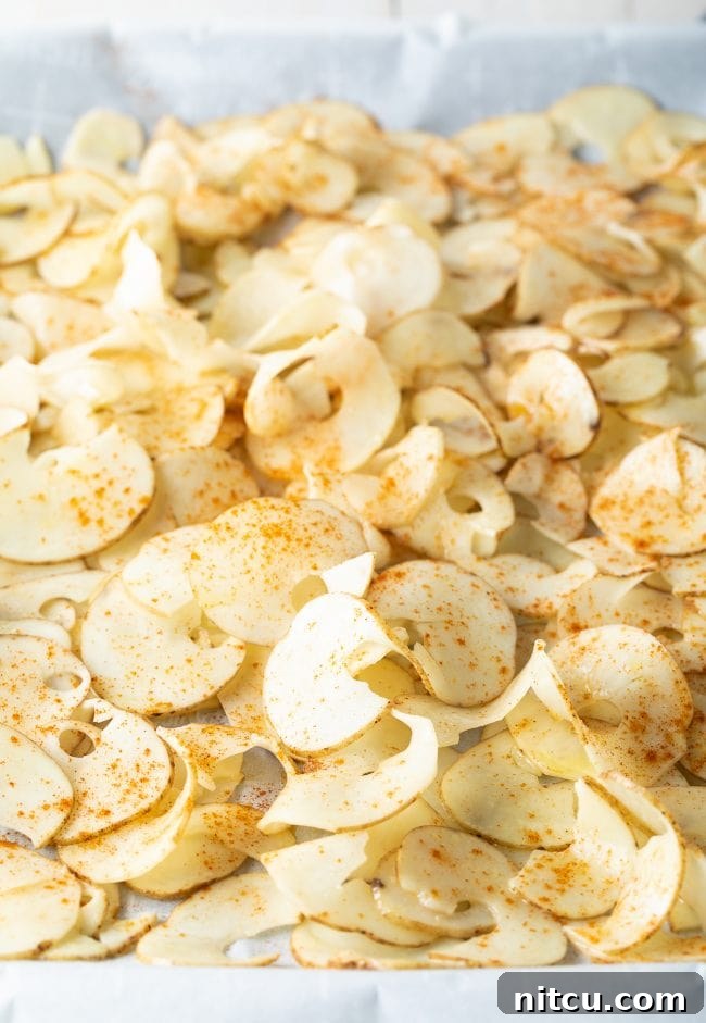 Ribbons of seasoned potatoes on a baking sheet.