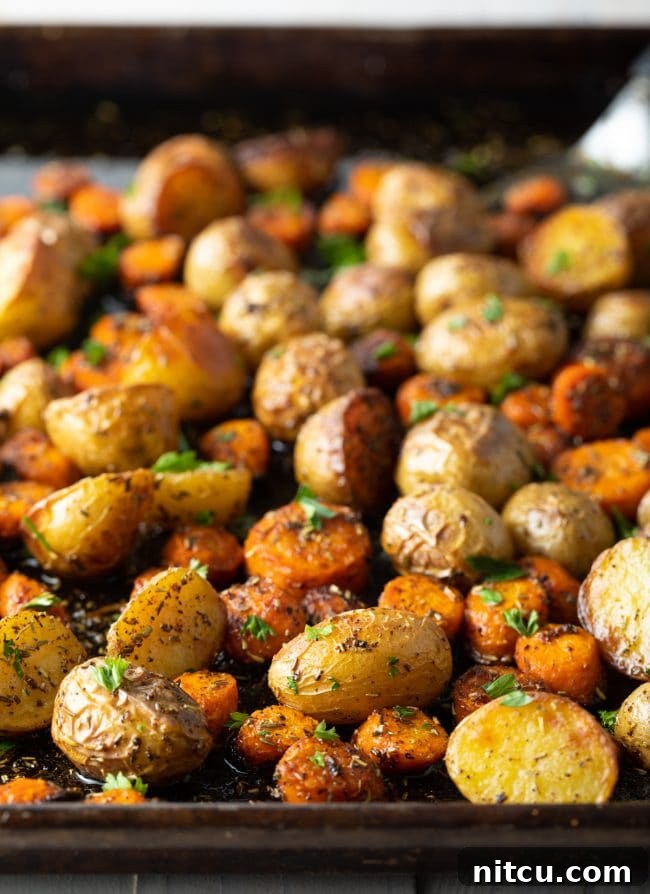 Potatoes, carrots, and herbs on a baking sheet