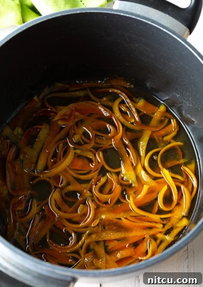 Orange Peel Confections 5 Orange peels gently simmering in a sweet syrup, illustrating the candying process.