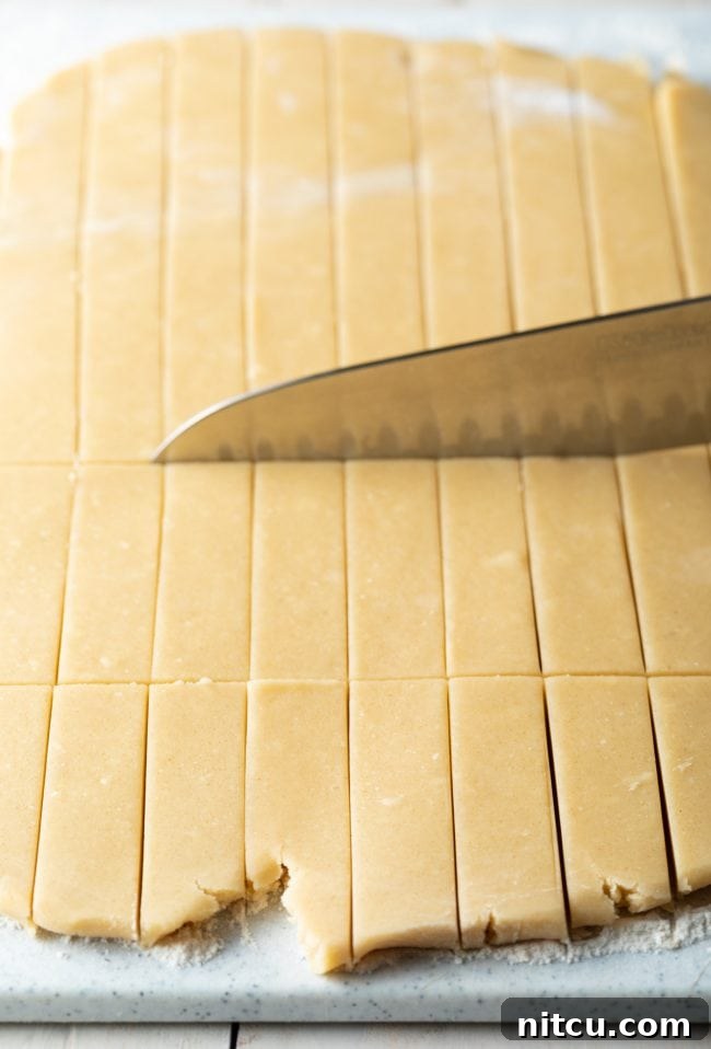 Buttery Scottish Shortbread Delight 6 Large chef's knife slicing the dough into small rectangles.